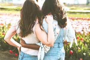two girls stand with each other - true friends signs